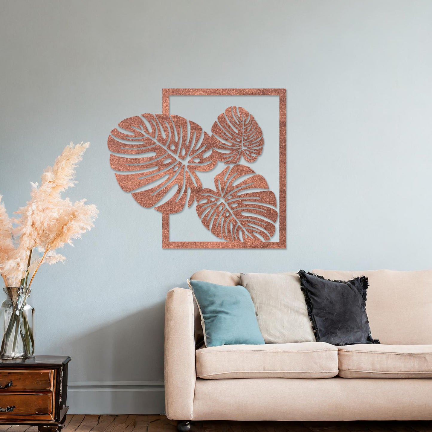 Wall art featuring a botanical design of overlapping monstera leaves framed within a rectangular border. The piece is displayed on a neutral wall within modern room decor, enhancing the natural and elegant aesthetic.
