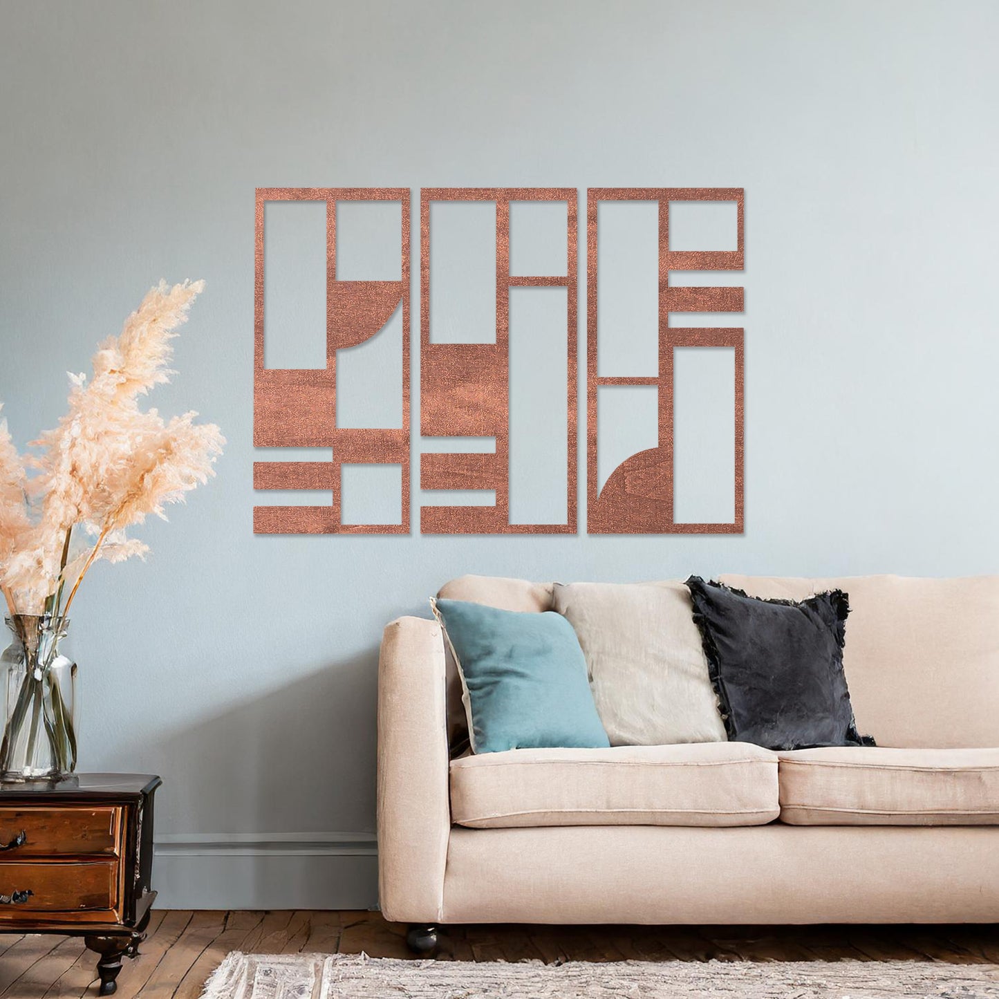 This image displays a modern, abstract triptych wall art piece featuring geometric patterns in dark tones. The artwork is placed above a simple desk setup with a plant and a chair, providing a stylish and minimalistic atmosphere suitable for a contemporary workspace. 