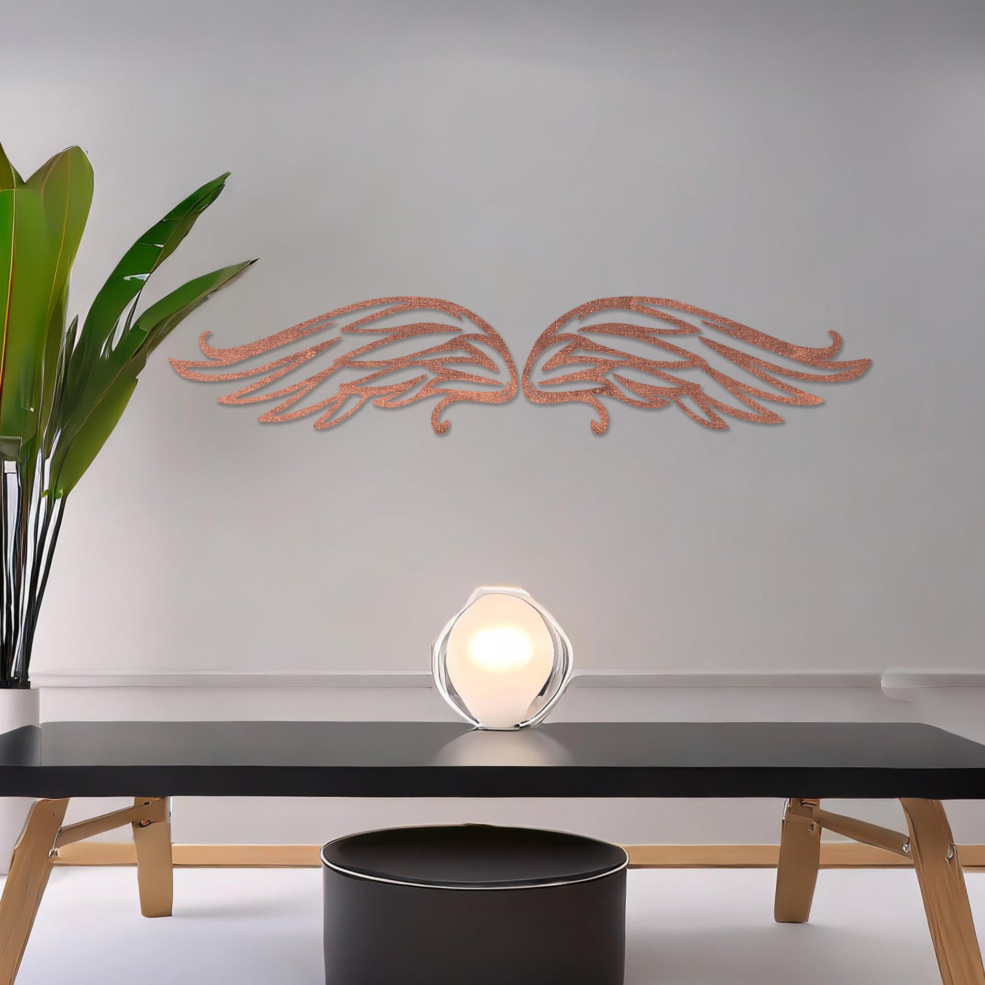 Wall art featuring a pair of intricately designed angel wings with flowing lines and graceful curves. The piece is displayed on a neutral wall within modern decor, adding a symbolic and elegant touch to the setting.