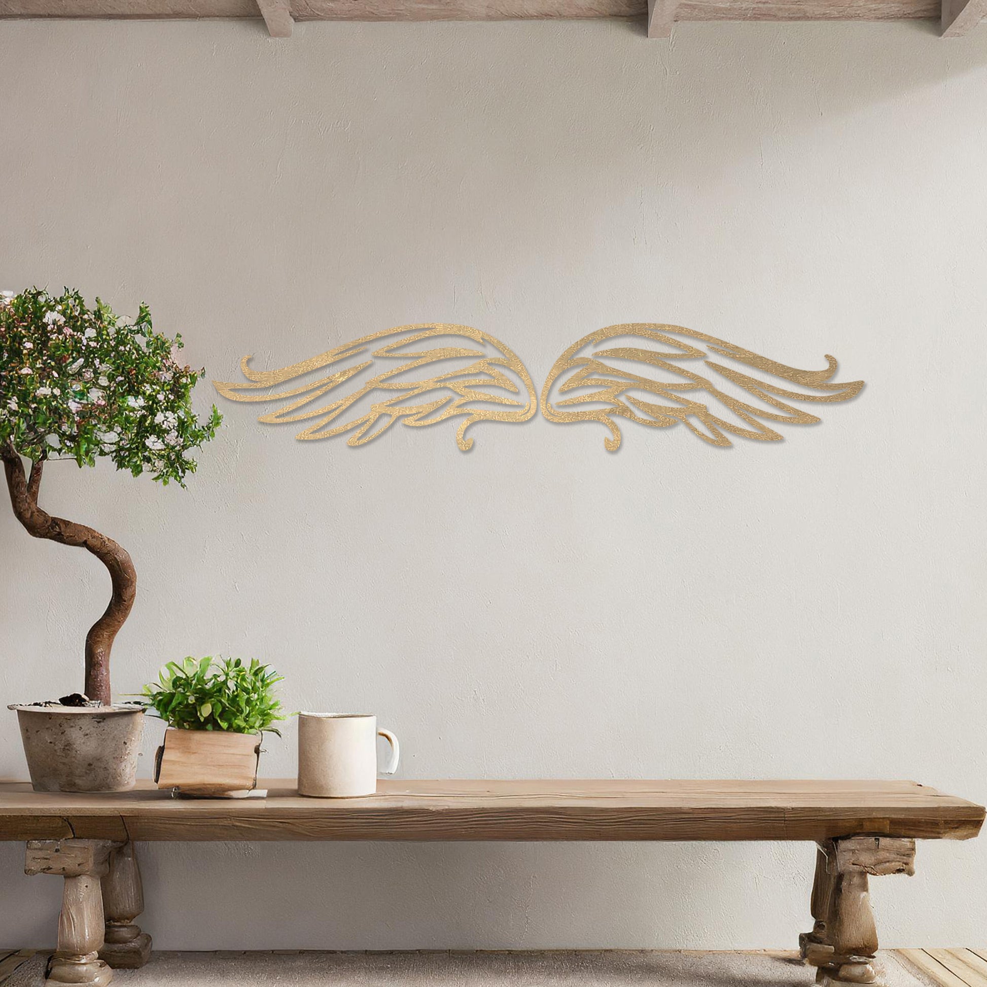 Wall art featuring a pair of intricately designed angel wings with flowing lines and graceful curves. The piece is displayed on a neutral wall within modern decor, adding a symbolic and elegant touch to the setting.