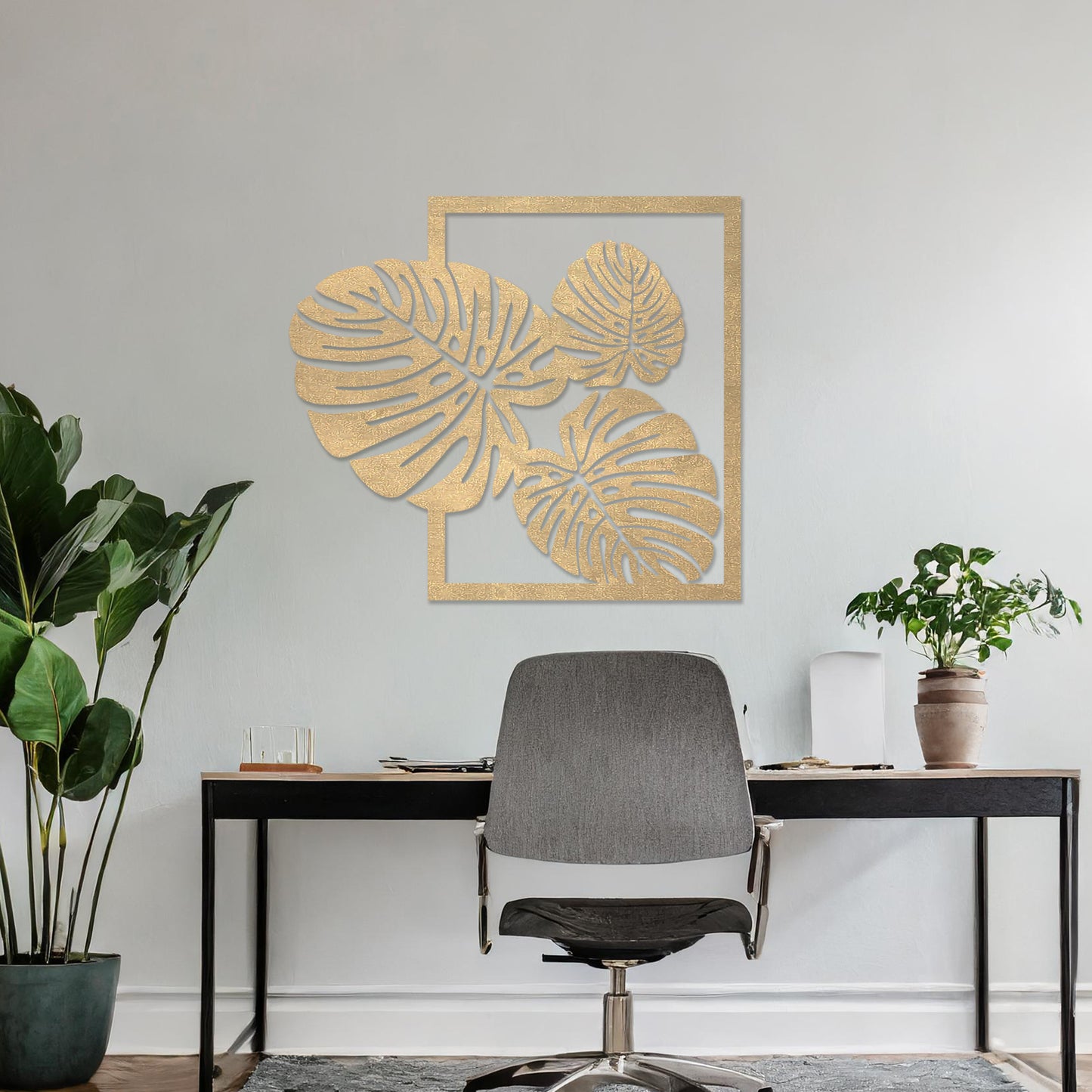 Wall art featuring a botanical design of overlapping monstera leaves framed within a rectangular border. The piece is displayed on a neutral wall within modern room decor, enhancing the natural and elegant aesthetic.