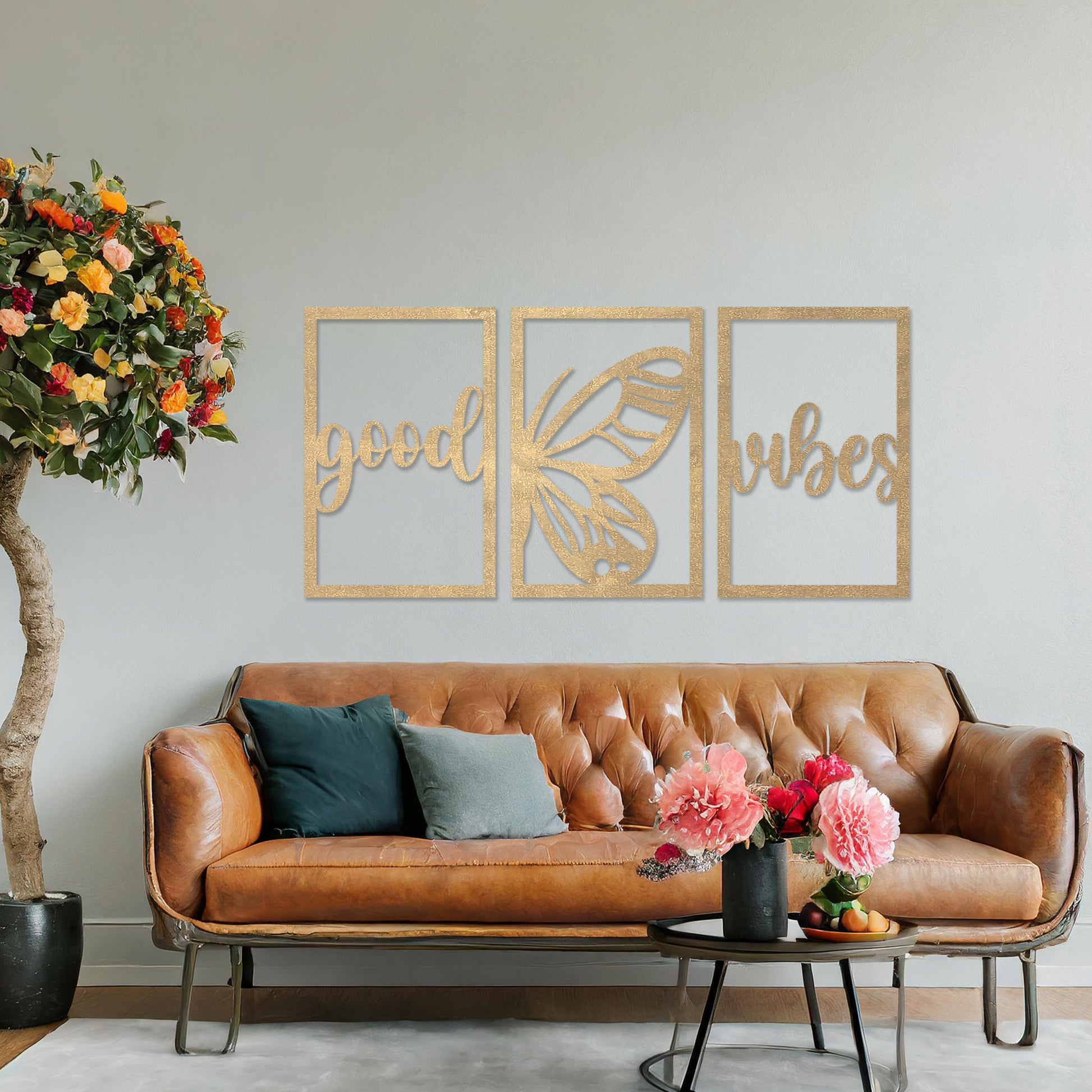 Wooden wall art featuring a three-panel design with the phrase "good vibes" and a butterfly motif in the centre. The artwork is placed on a neutral wall in modern room decor, highlighting its uplifting design.