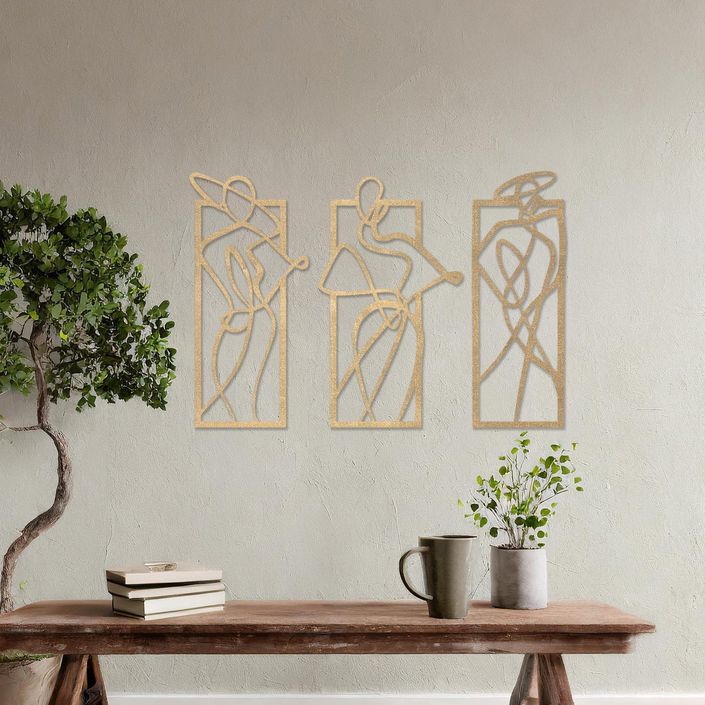 Wooden wall art design featuring three abstract figures in flowing lines, each in its own rectangular frame, placed on a neutral wall with modern room decor. The design evokes movement and elegance through minimalistic, artistic shapes.