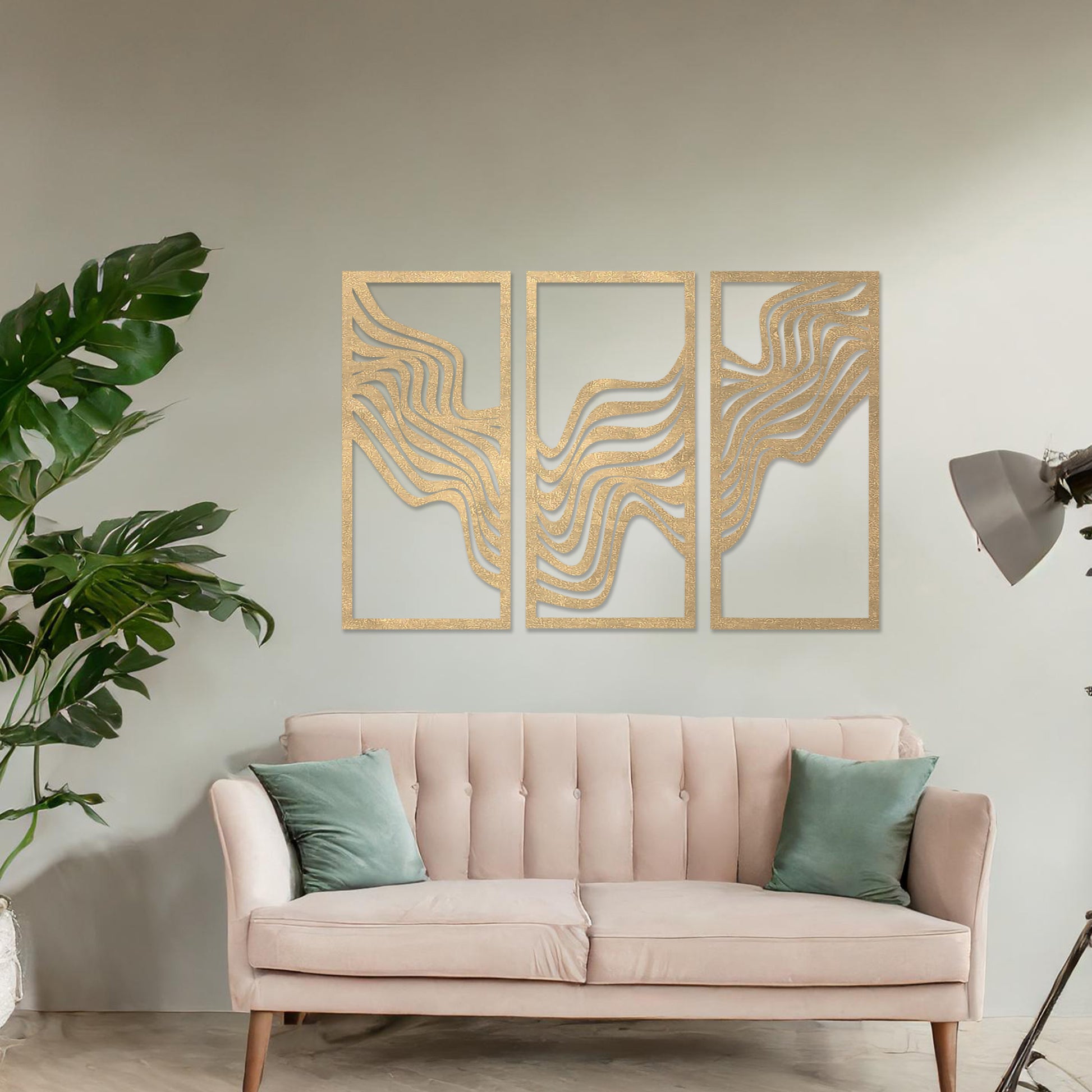 This image displays a modern triptych wall art design featuring flowing wave-like lines. The abstract patterns create a dynamic and visually appealing composition, adding an elegant touch to the living room's decor, complemented by a colourful sofa and floor lighting.