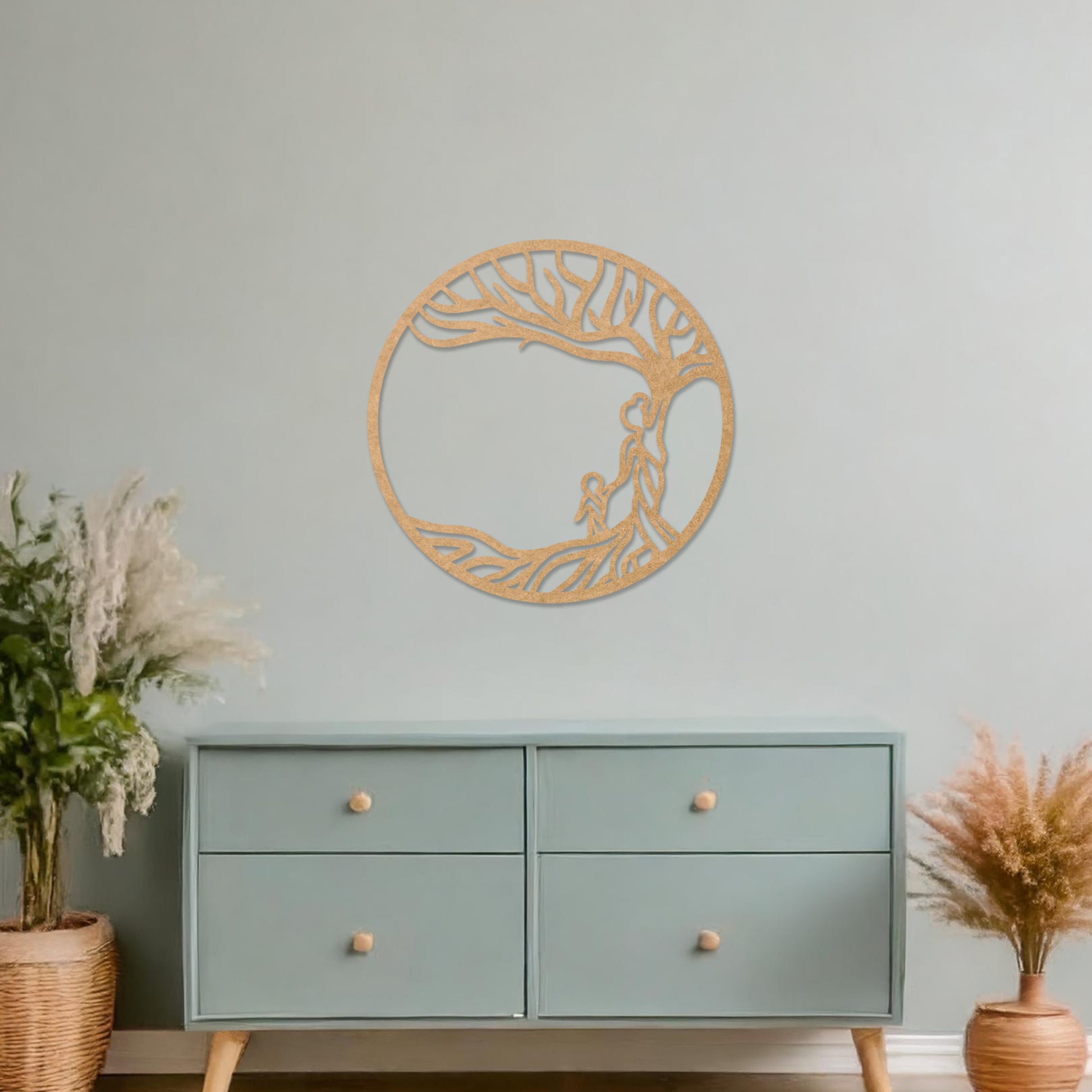 Wooden wall art featuring a circular design with a tree and two human figures under its branches, symbolising family and connection. The artwork is displayed on a neutral wall within modern room decor, highlighting its meaningful design.