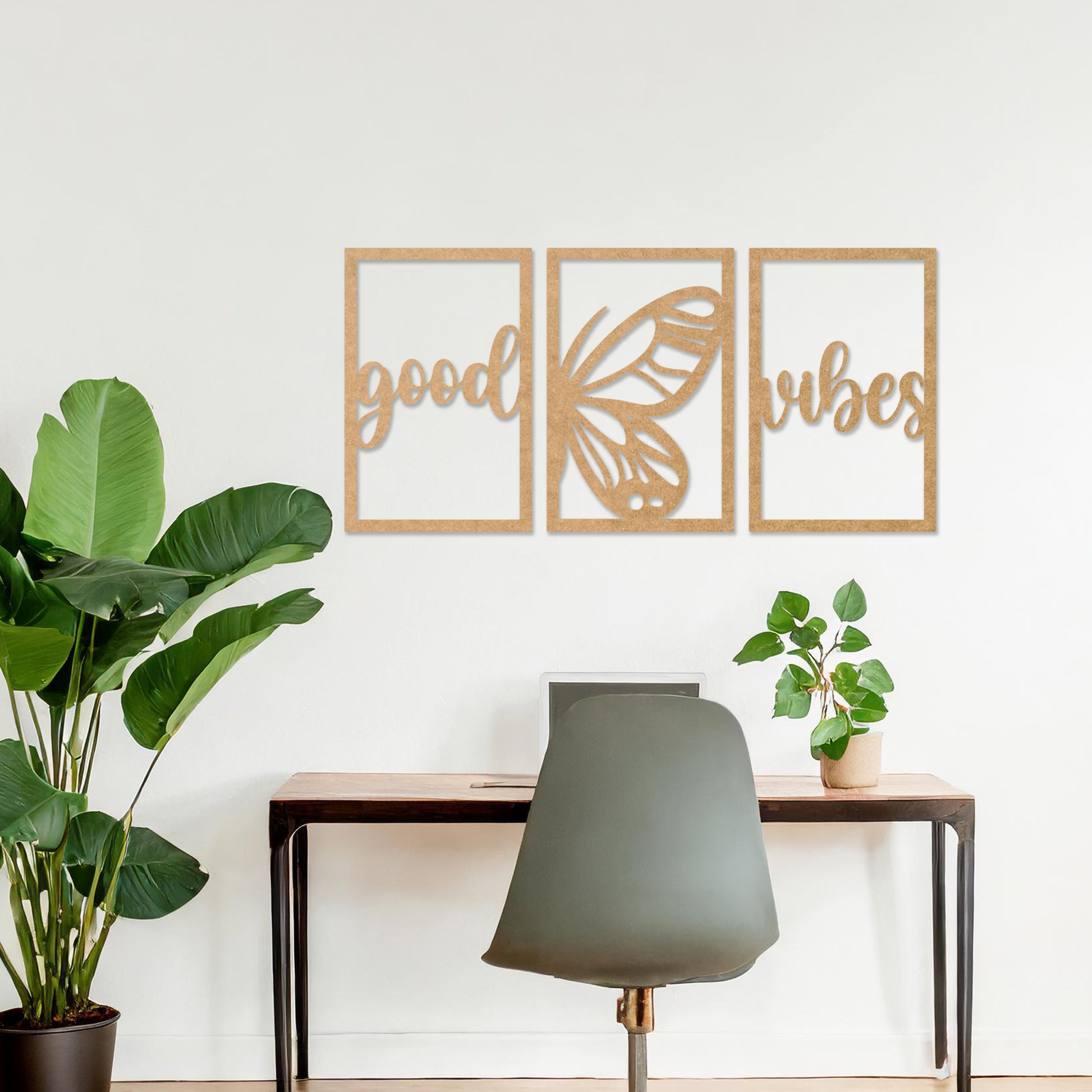 Wooden wall art featuring a three-panel design with the phrase "good vibes" and a butterfly motif in the centre. The artwork is placed on a neutral wall in modern room decor, highlighting its uplifting design.