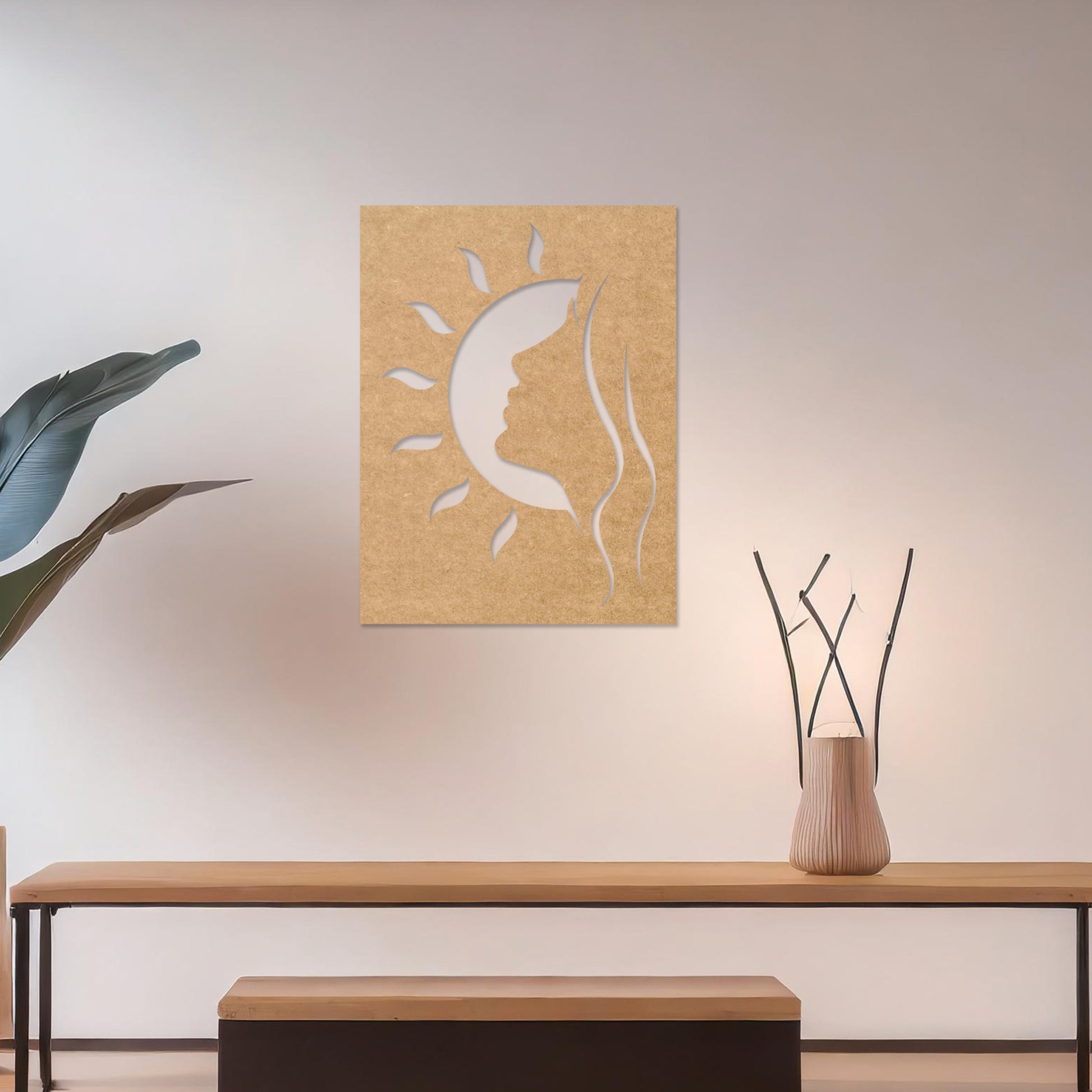 A rectangular wall art piece featuring a silhouette of a face intertwined with a crescent moon and radiating sun rays. The artwork is displayed on a neutral wall in a modern living room