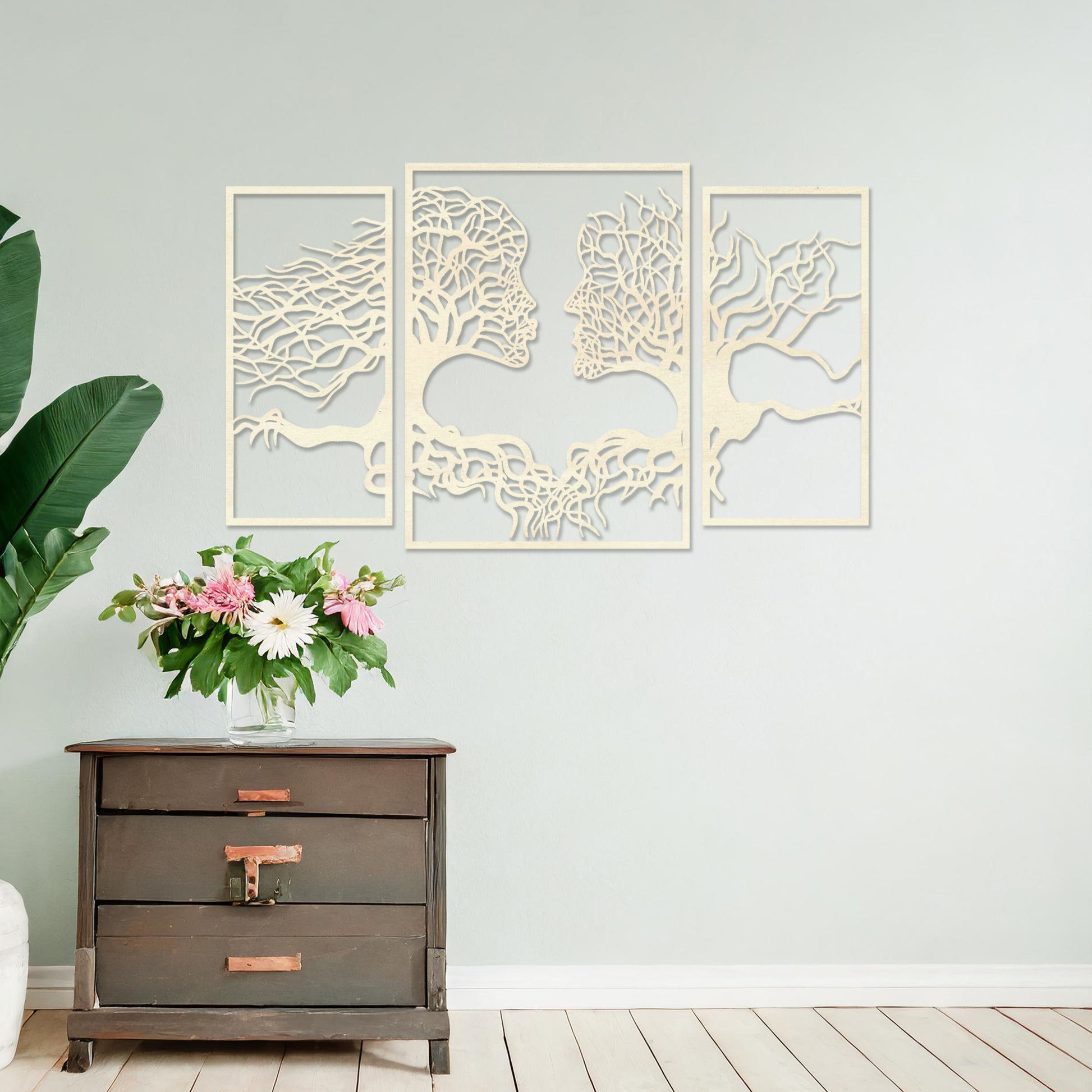 Wooden wall art showcasing a striking design of intertwined tree branches forming human profiles, placed on a neutral wall within modern room decor, highlighting its artistic and symbolic craftsmanship.
