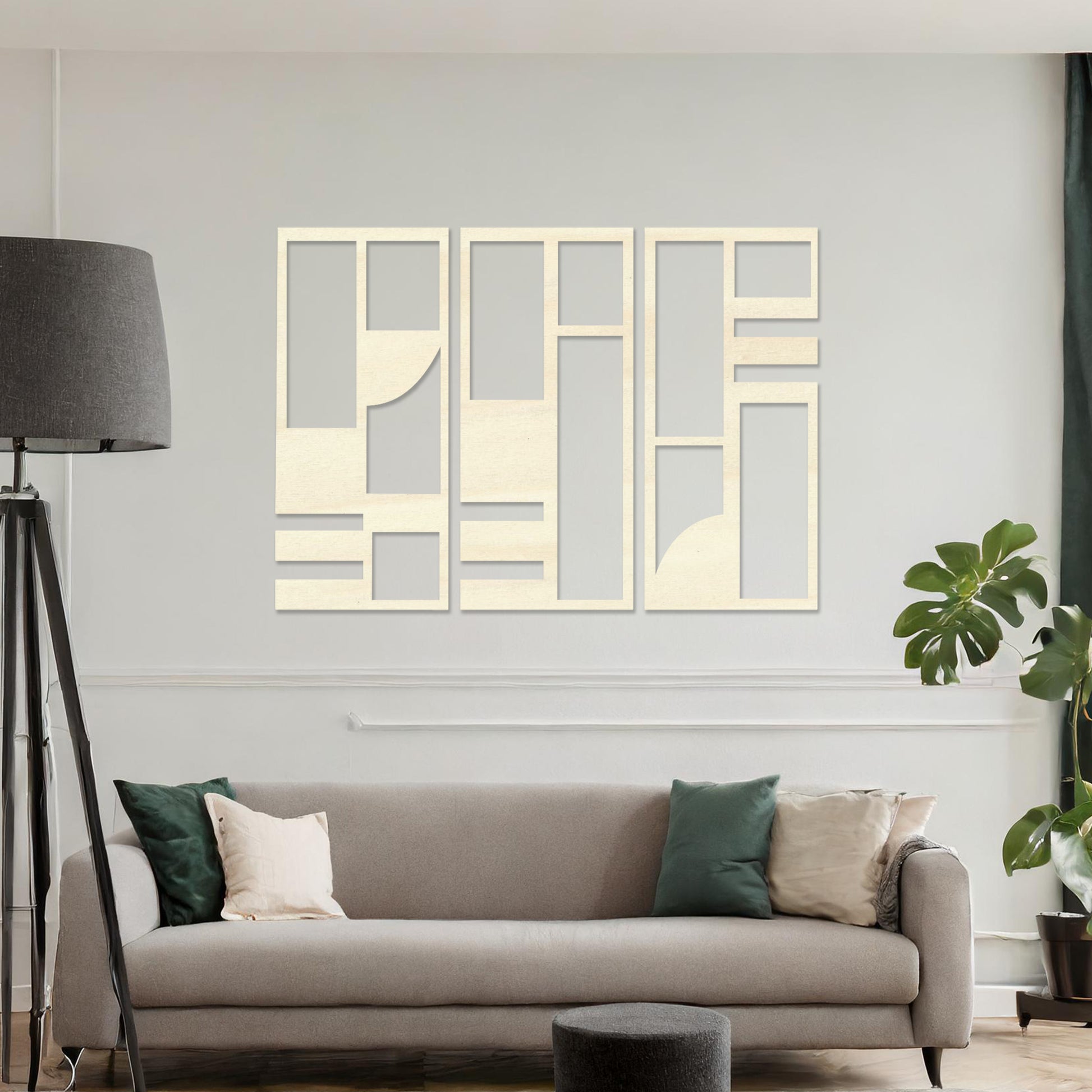 This image displays a modern, abstract triptych wall art piece featuring geometric patterns in dark tones. The artwork is placed above a simple desk setup with a plant and a chair, providing a stylish and minimalistic atmosphere suitable for a contemporary workspace. 