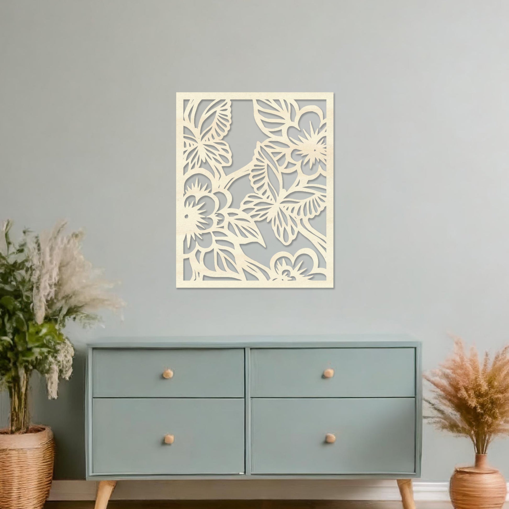 Wooden wall art featuring a square design with intricate floral and leaf patterns, showcasing a vibrant natural theme. The artwork is displayed on a neutral wall within modern room decor, highlighting its artistic and elegant appeal.