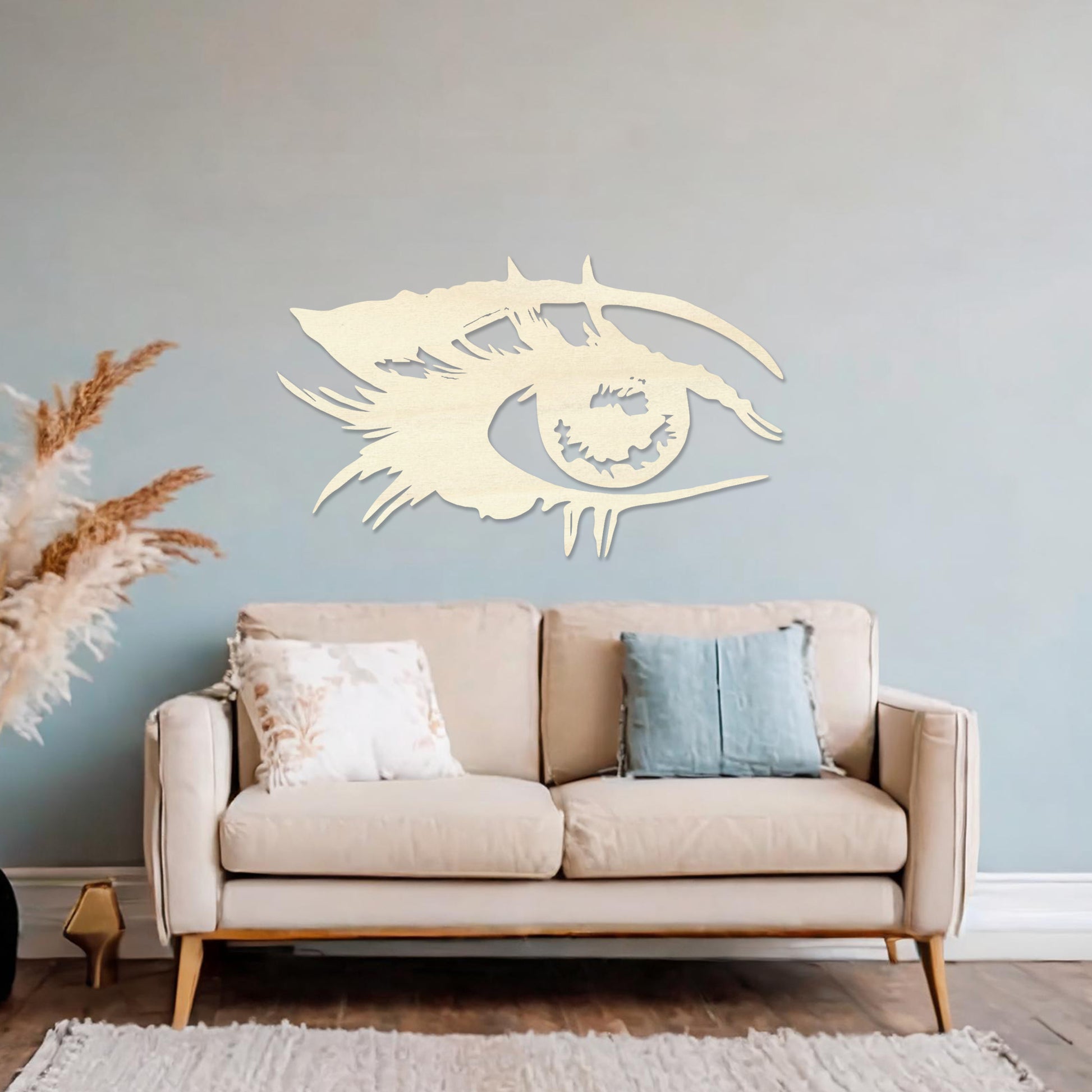 Wooden wall art featuring a stylised eye design with intricate detailing of lashes and bold lines. The artwork is displayed on a neutral wall within modern room decor, emphasising its artistic and striking pattern.