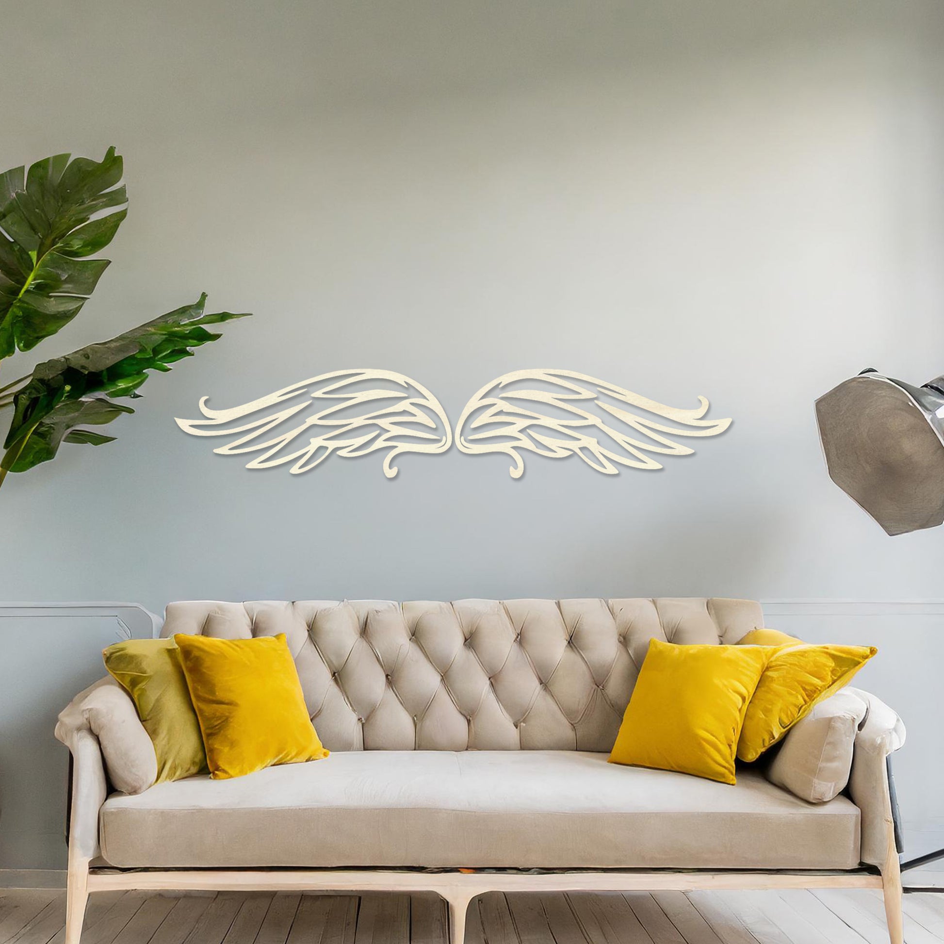 Wall art featuring a pair of intricately designed angel wings with flowing lines and graceful curves. The piece is displayed on a neutral wall within modern decor, adding a symbolic and elegant touch to the setting.