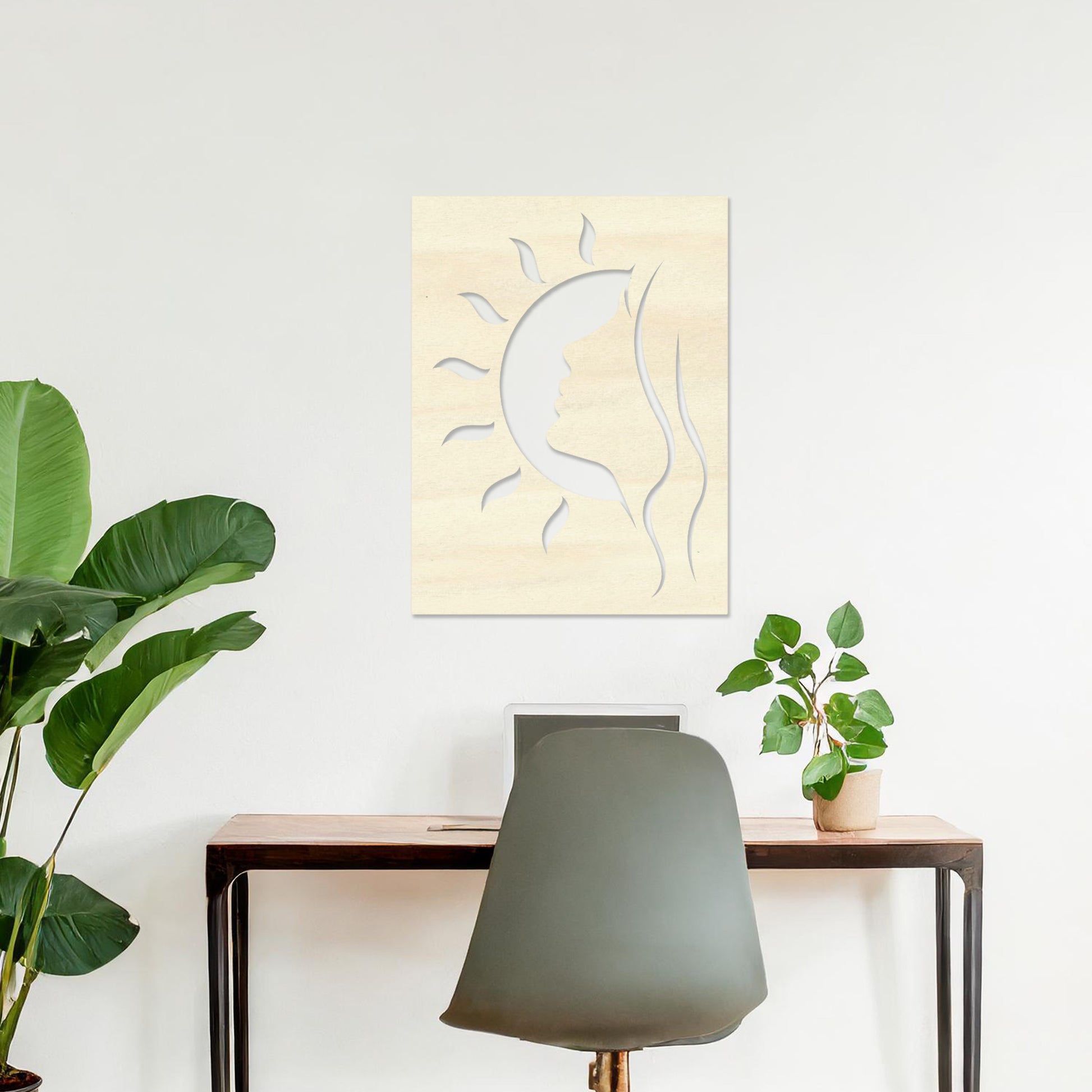 A rectangular wall art piece featuring a silhouette of a face intertwined with a crescent moon and radiating sun rays. The artwork is displayed on a neutral wall in a modern living room