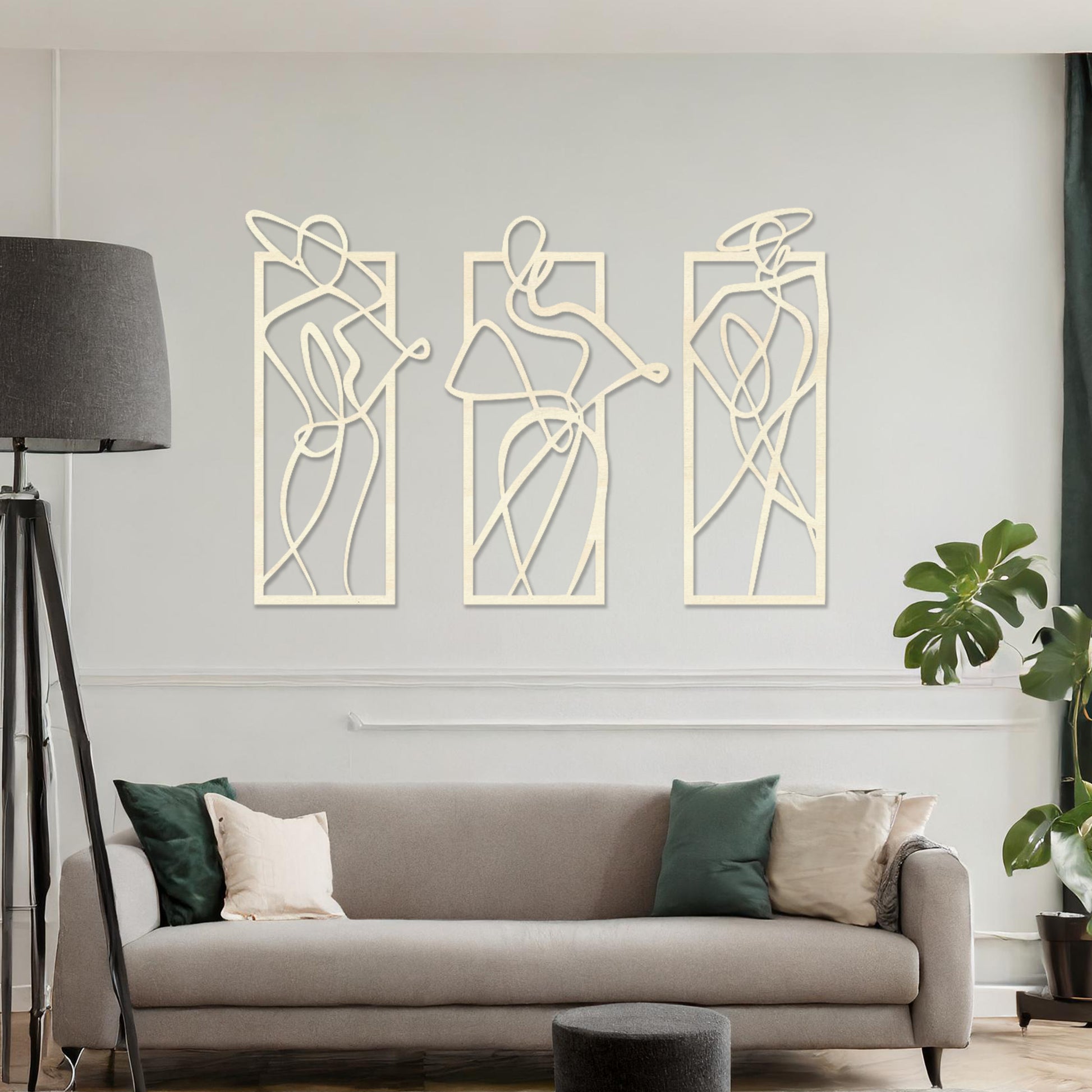 Wooden wall art design featuring three abstract figures in flowing lines, each in its own rectangular frame, placed on a neutral wall with modern room decor. The design evokes movement and elegance through minimalistic, artistic shapes.