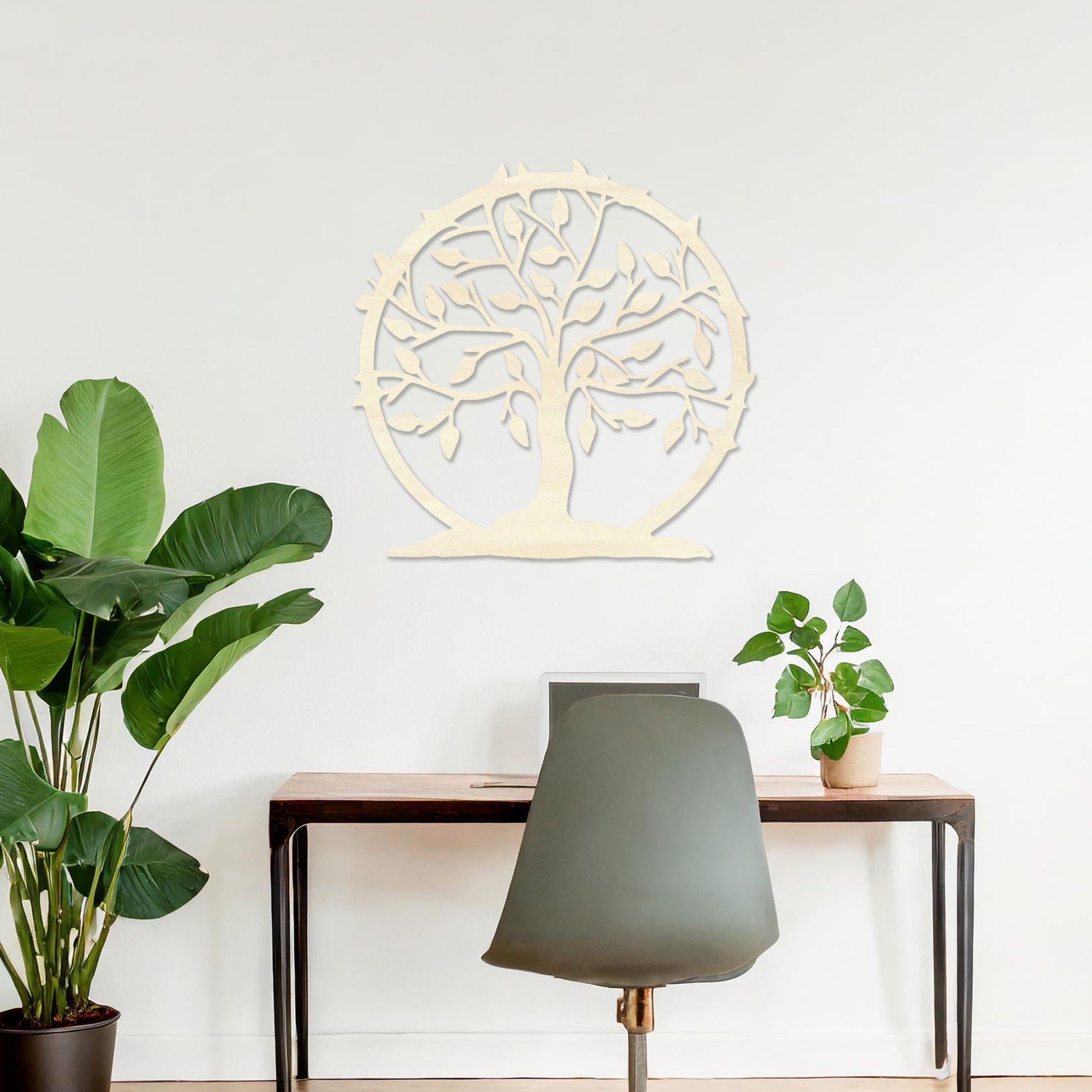 Wooden wall art featuring a circular tree design with branches, leaves, and a border of thorns. The artwork is displayed on a neutral wall within modern room decor, emphasising its natural and symbolic charm.