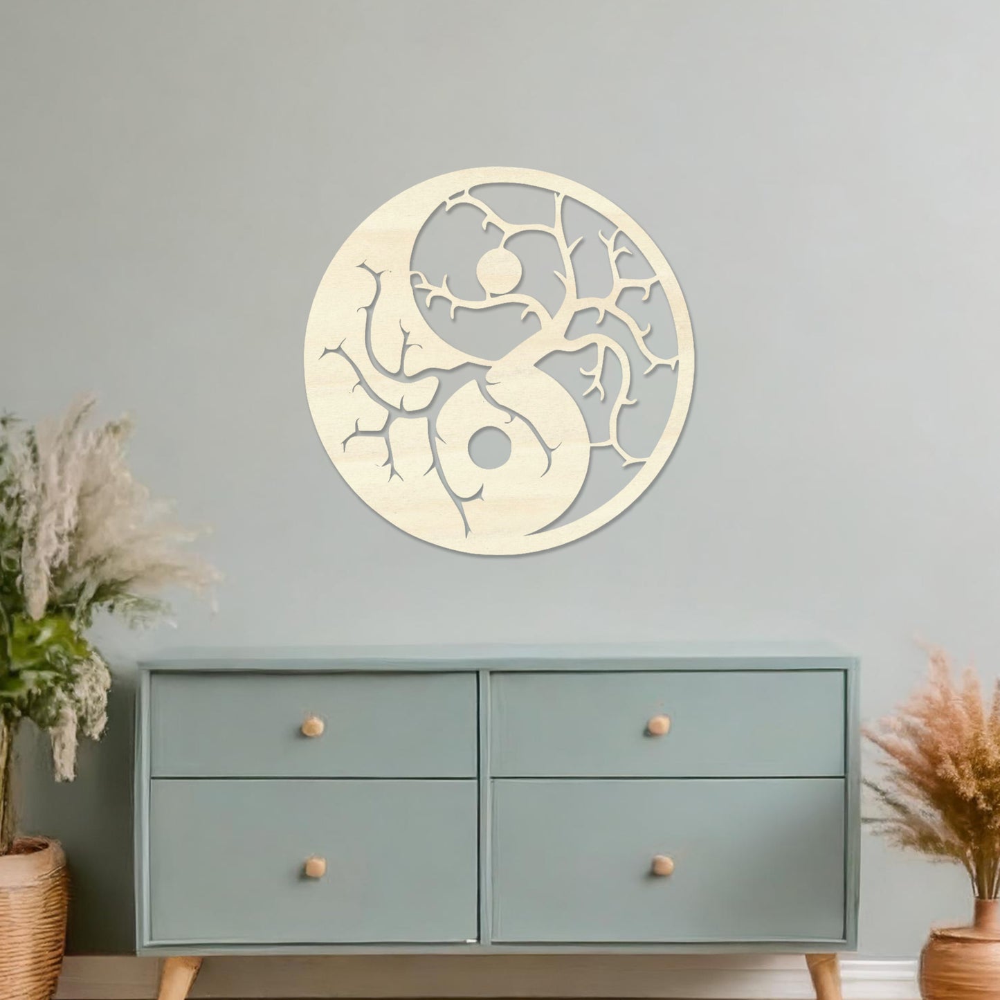 Wall art featuring a yin-yang design with tree branches integrated into each half, symbolising balance and harmony. The piece is displayed on a neutral wall within modern decor, adding a meaningful and artistic focal point to the space.