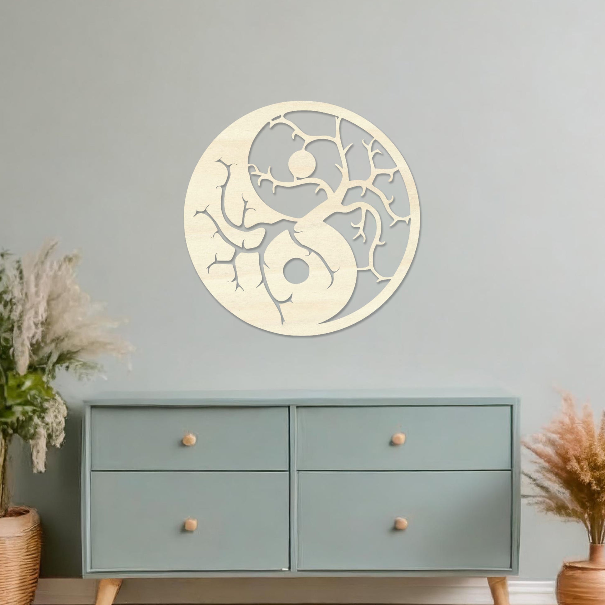 Wall art featuring a yin-yang design with tree branches integrated into each half, symbolising balance and harmony. The piece is displayed on a neutral wall within modern decor, adding a meaningful and artistic focal point to the space.