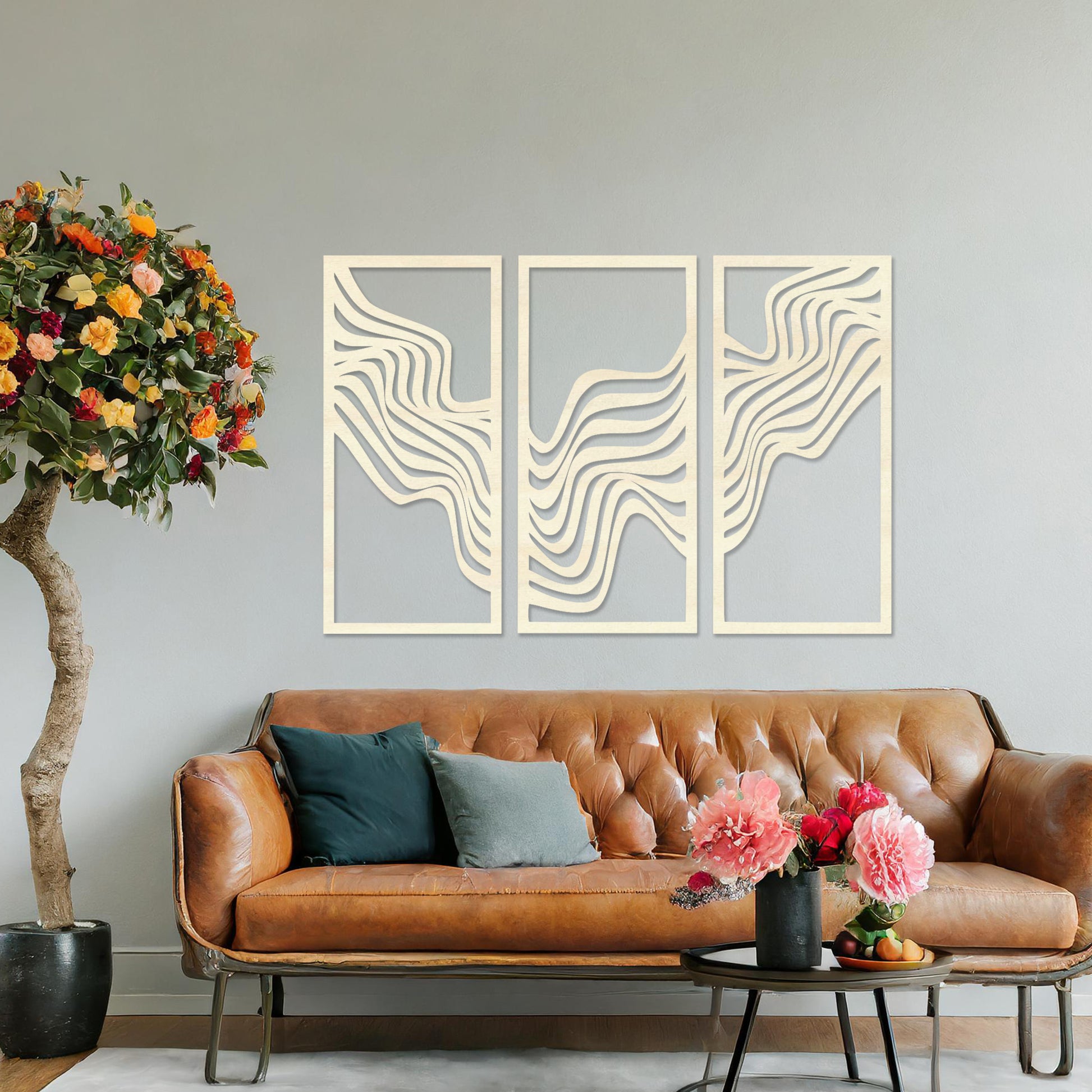 This image displays a modern triptych wall art design featuring flowing wave-like lines. The abstract patterns create a dynamic and visually appealing composition, adding an elegant touch to the living room's decor, complemented by a colourful sofa and floor lighting.