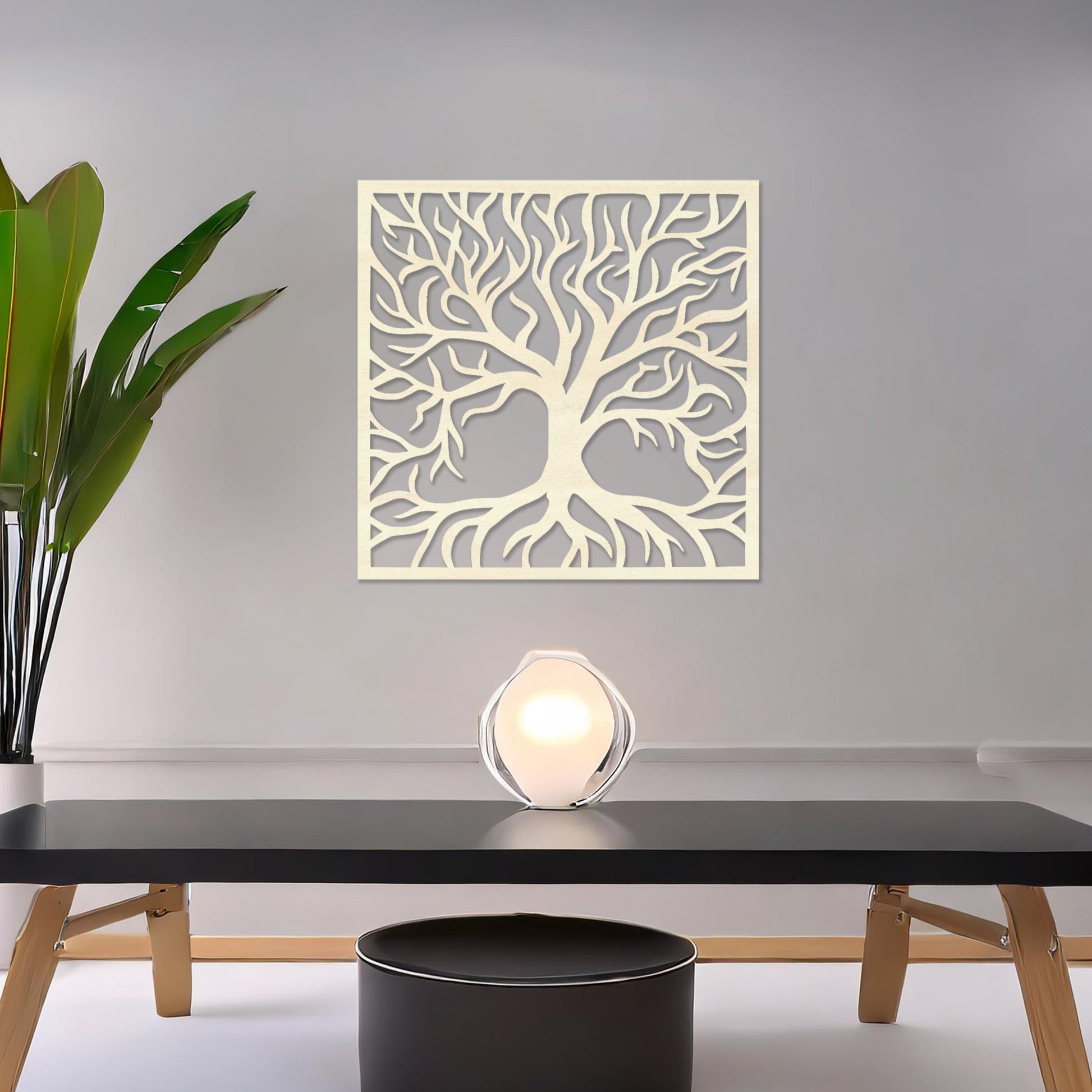 A square wall art piece depicting an intricate tree with branching limbs and visible roots. The artwork is displayed on a neutral wall in a modern room