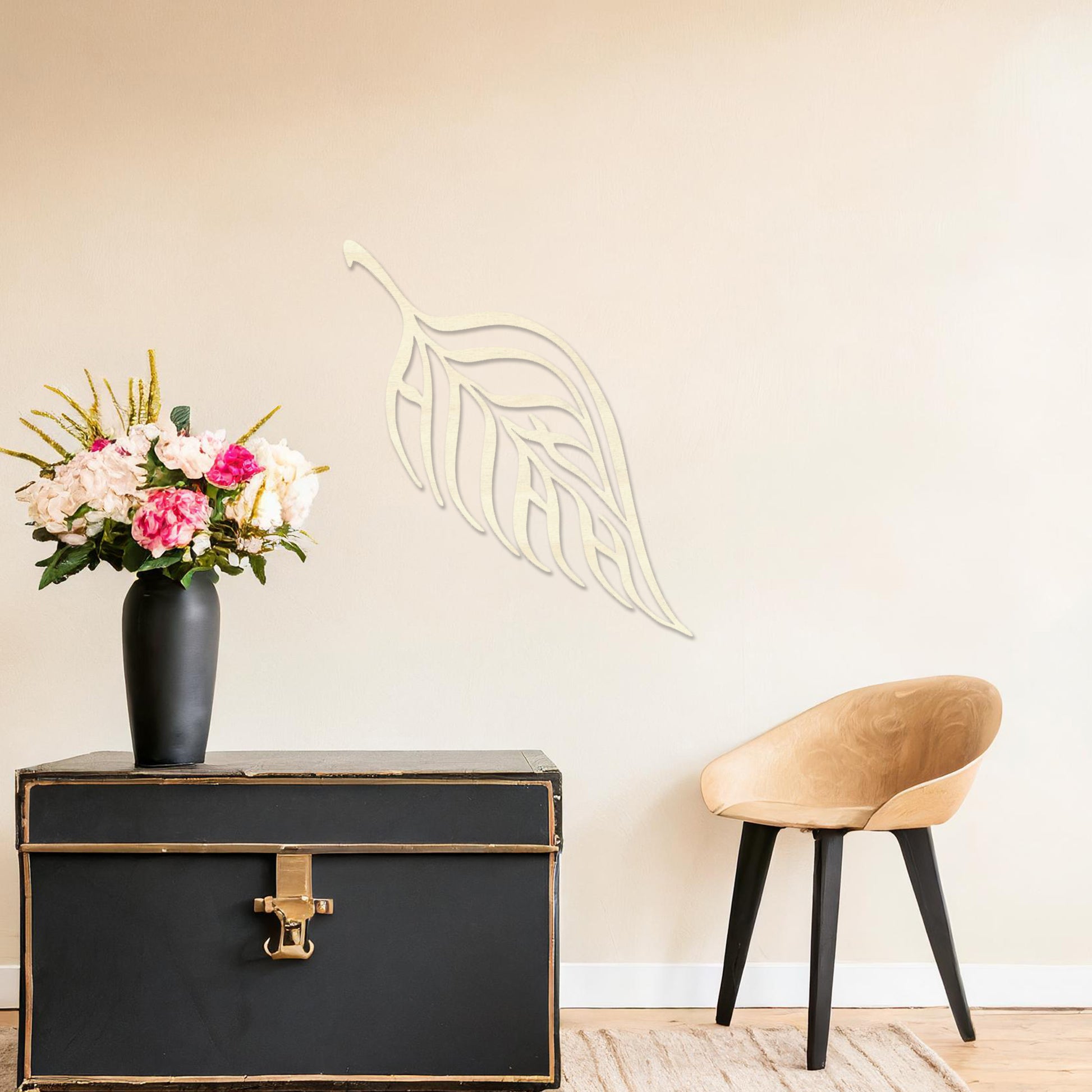 Wooden wall art featuring a single leaf design with elegant, flowing lines and intricate cut-outs. The artwork is displayed on a neutral wall within modern room decor, emphasising its minimalistic and natural aesthetic.