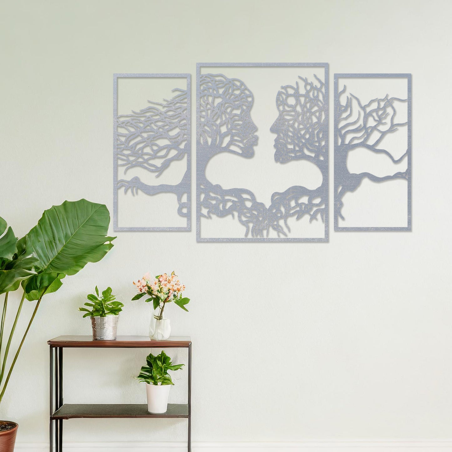 Wooden wall art showcasing a striking design of intertwined tree branches forming human profiles, placed on a neutral wall within modern room decor, highlighting its artistic and symbolic craftsmanship.