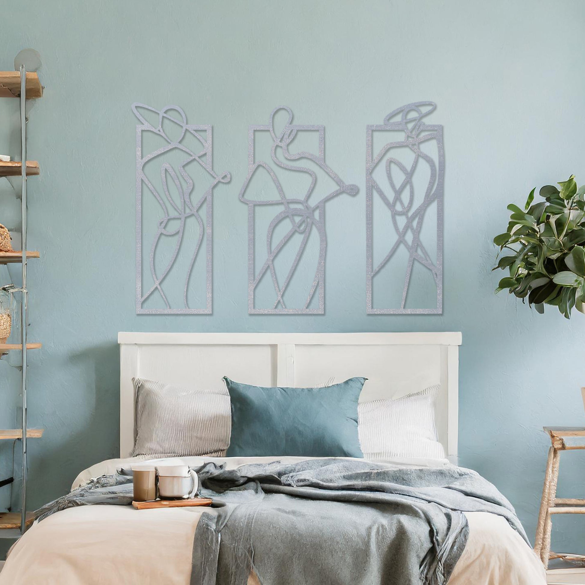 Wooden wall art design featuring three abstract figures in flowing lines, each in its own rectangular frame, placed on a neutral wall with modern room decor. The design evokes movement and elegance through minimalistic, artistic shapes.