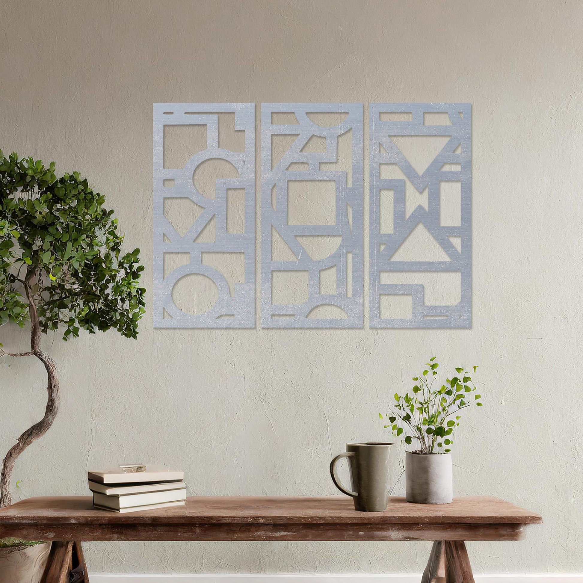 This image features a vibrant, modern triptych wall art design made of geometric shapes and patterns. The bold black designs contrast against a light green wall, complementing the stylish sofa below. 