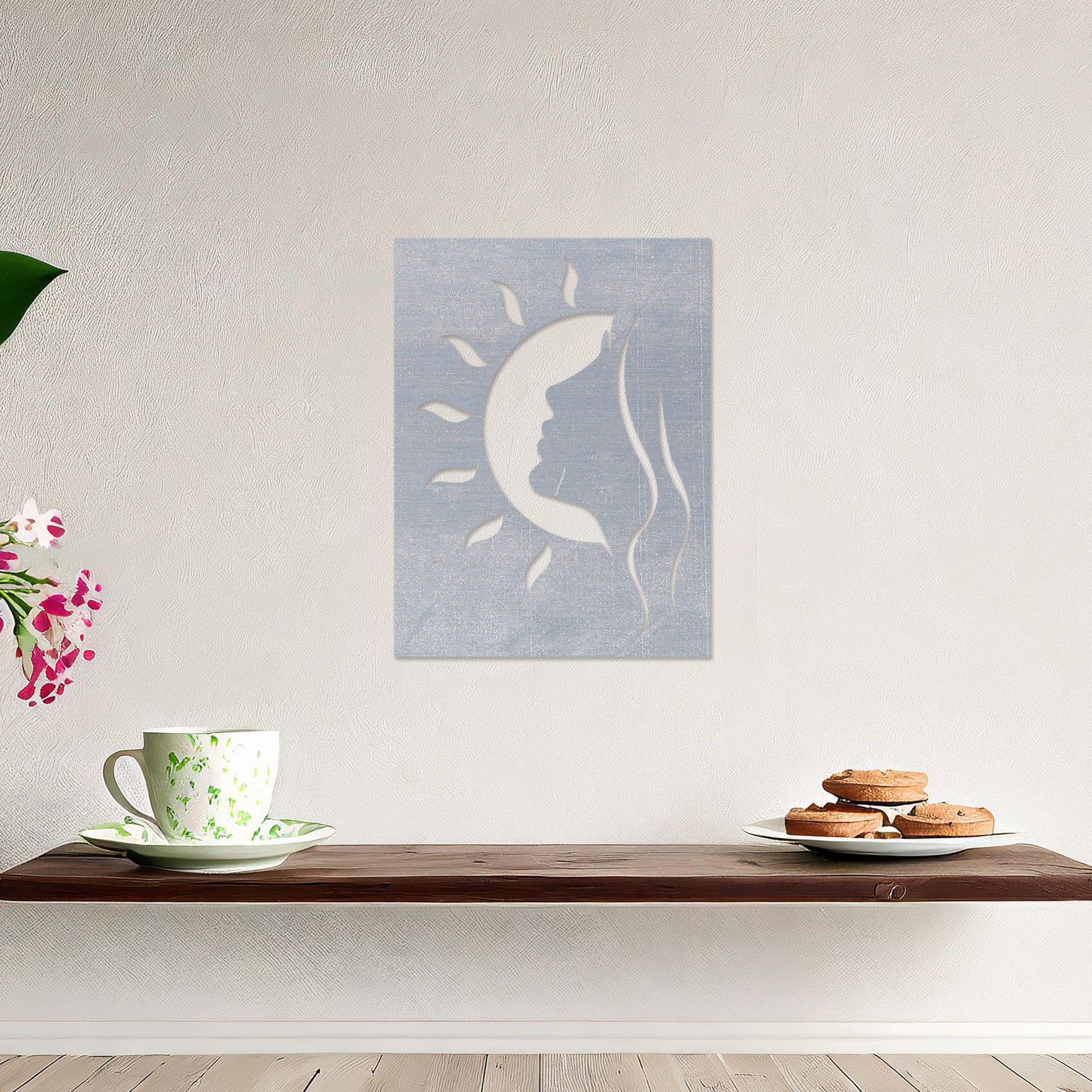 A rectangular wall art piece featuring a silhouette of a face intertwined with a crescent moon and radiating sun rays. The artwork is displayed on a neutral wall in a modern living room