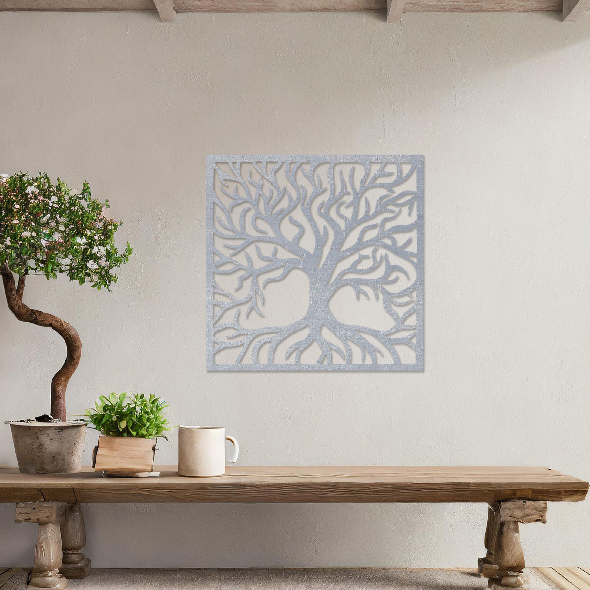 A square wall art piece depicting an intricate tree with branching limbs and visible roots. The artwork is displayed on a neutral wall in a modern room