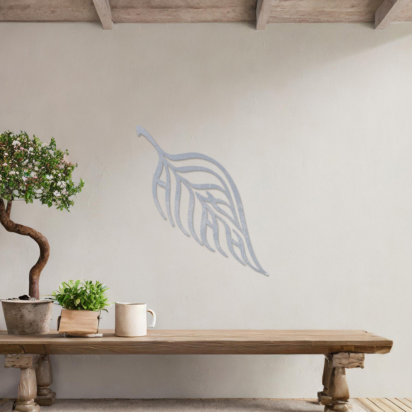 Wooden wall art featuring a single leaf design with elegant, flowing lines and intricate cut-outs. The artwork is displayed on a neutral wall within modern room decor, emphasising its minimalistic and natural aesthetic.