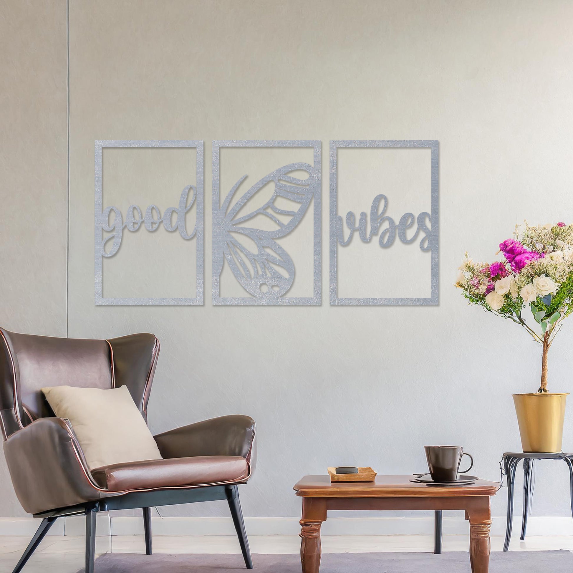 Wooden wall art featuring a three-panel design with the phrase "good vibes" and a butterfly motif in the centre. The artwork is placed on a neutral wall in modern room decor, highlighting its uplifting design.