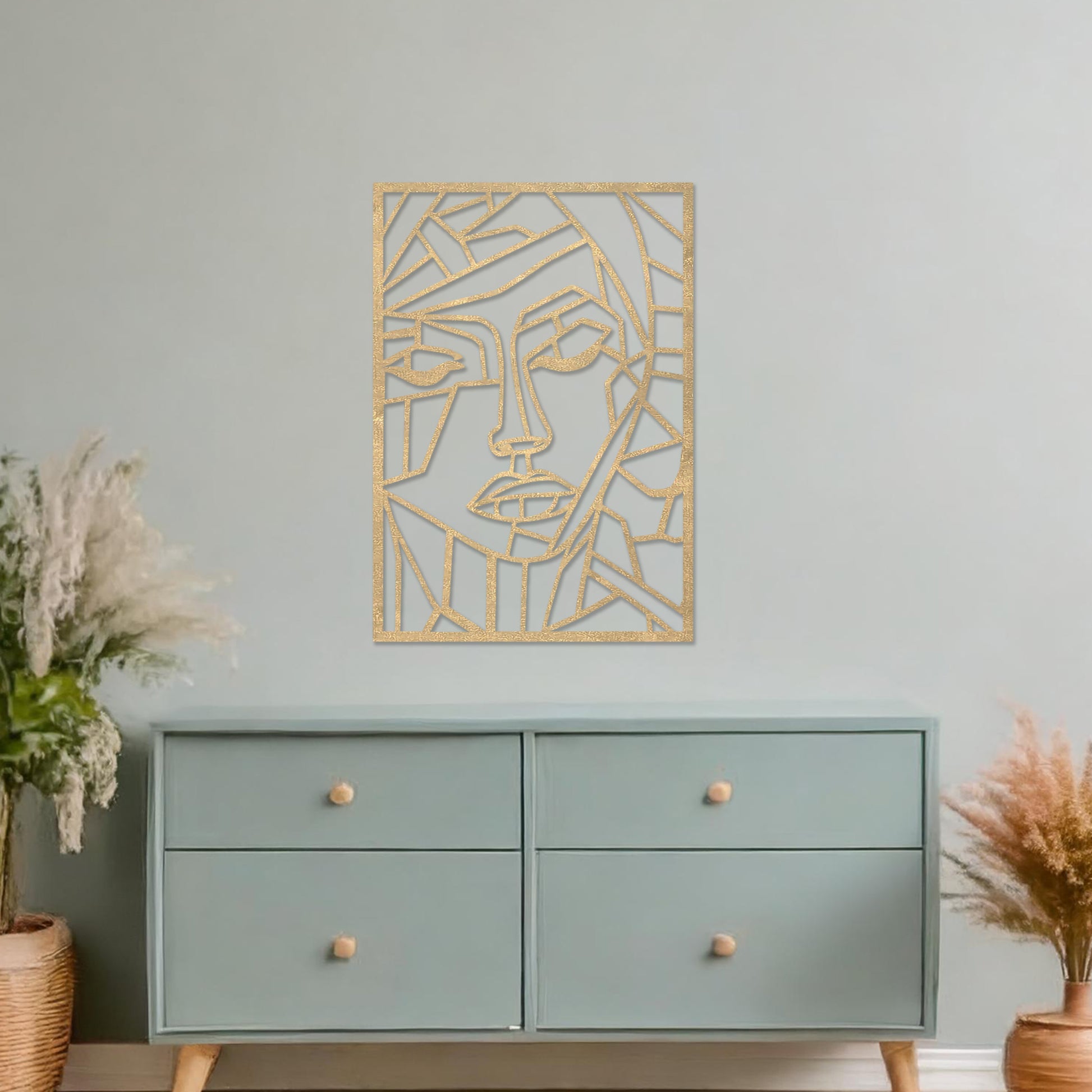 A rectangular wall art piece featuring an abstract face design composed of geometric shapes and clean lines. The artwork is displayed on a neutral wall in a contemporary living room, 